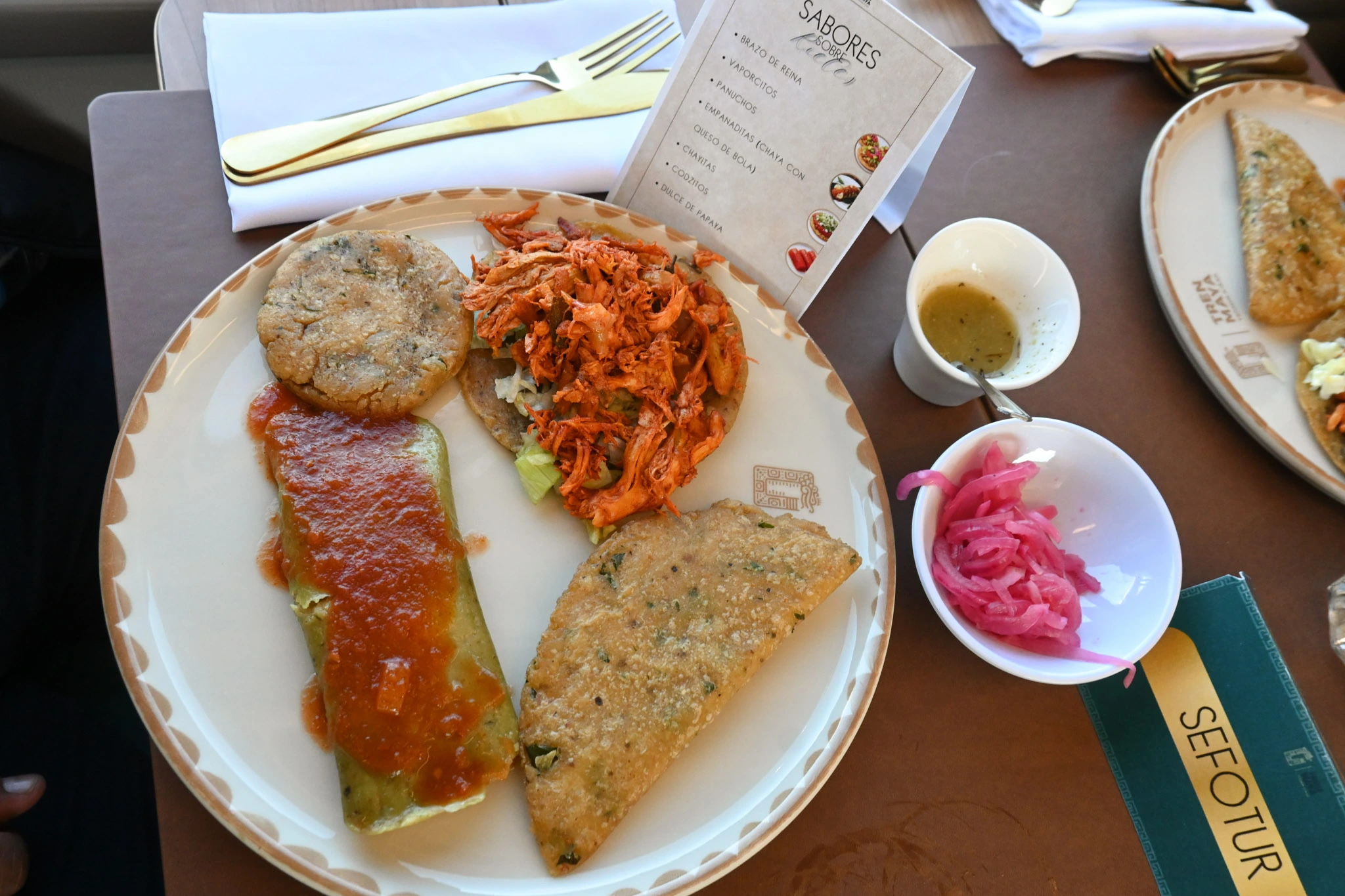 Plato con tamal, empanadas, salbute en tren restaurante